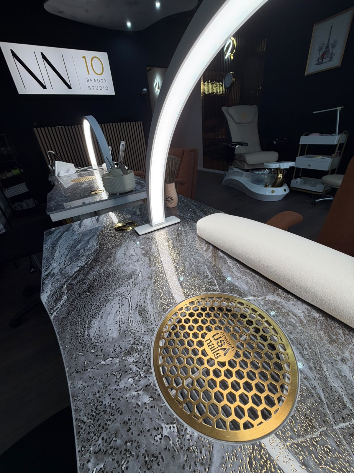 Maniküre-Tisch im NN10 Beauty Studio aus der Nähe — Marmorplatte mit goldener Absaugung, Bogenlampe und Handauflage
