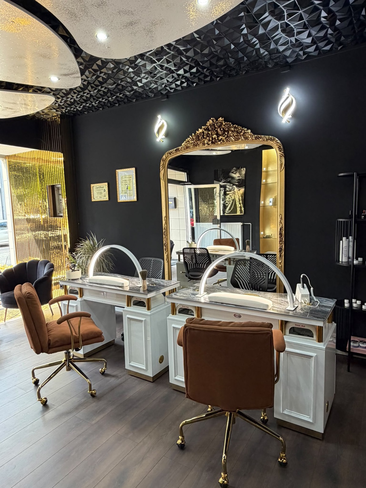 Maniküre-Arbeitsplätze im NN10 Beauty Studio — weiße Tische mit Marmorplatten und goldgerahmter Spiegel vor schwarzer Wand