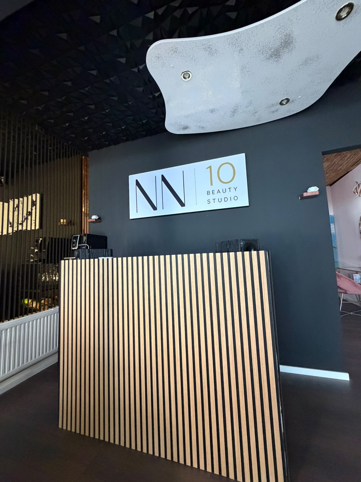 Empfangsbereich des NN10 Beauty Studios mit beleuchtetem Logo an schwarzer Wand